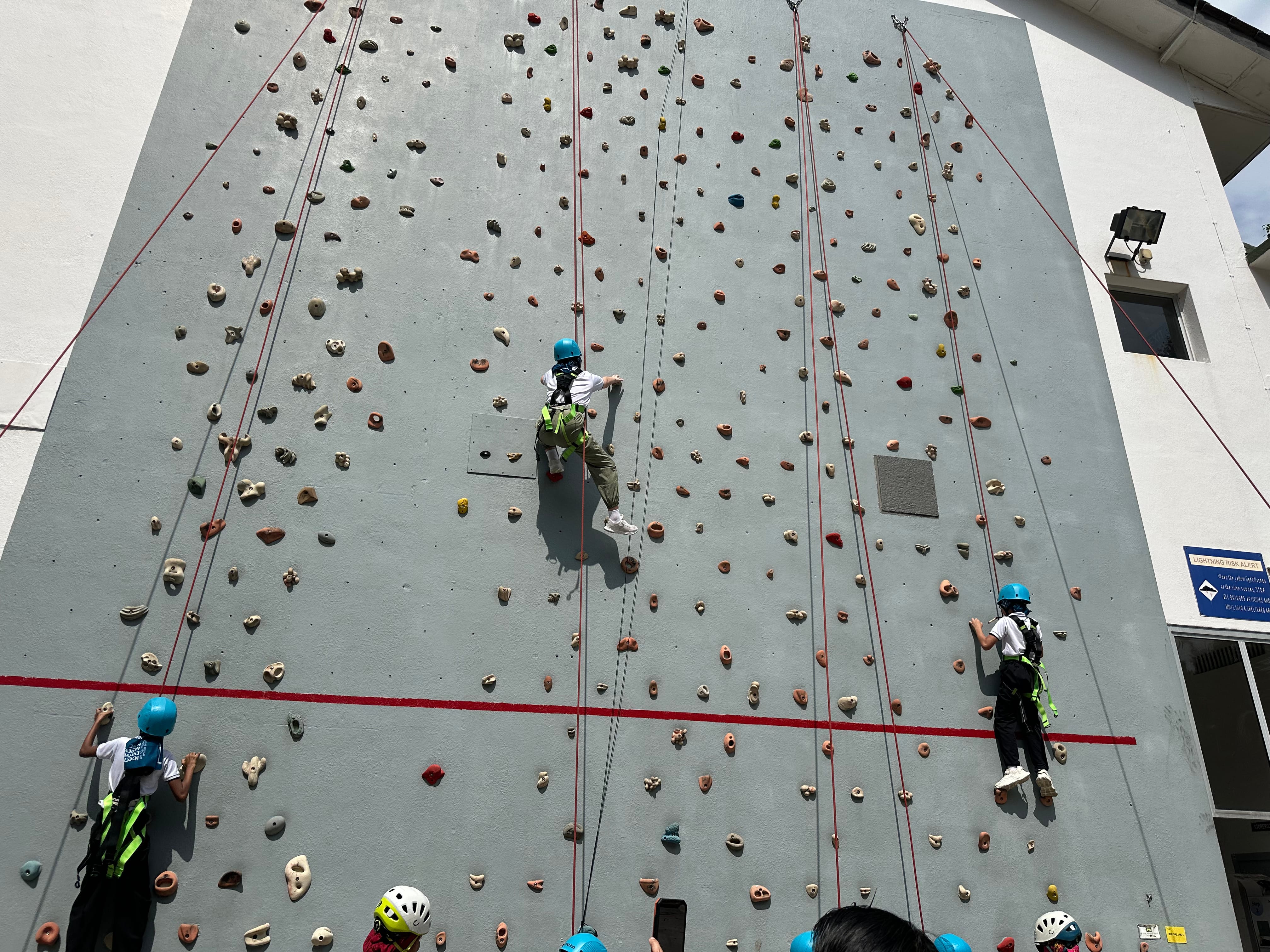 The climbing wall in full swing, with students progressing at their own pace, safely supported by their ropes throughout.